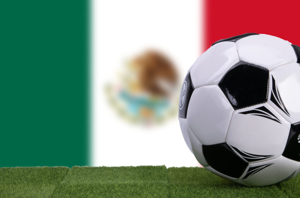 A soccer ball in front of the Mexican flag