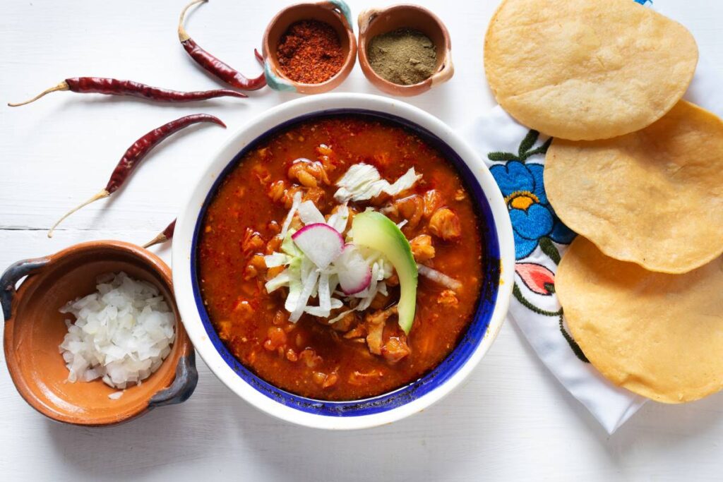 Red Pozole on a table with tortillas